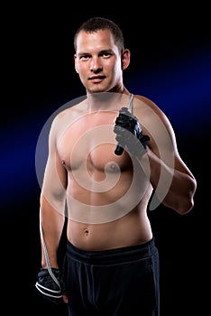 Athlete in gloves with bare torso holding a jump rope