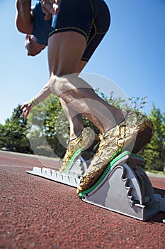 Athlete in Gold Shoes on Starting Blocks