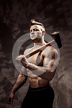 Athlete and hammer. guy with a nice muscle fitness, bodybuilder coach hold big metal hammer