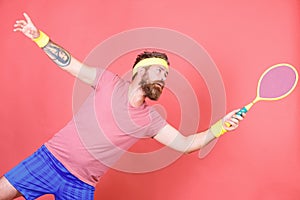 Athlete hipster hold tennis racket in hand red background. Man bearded hipster wear sport outfit. Tennis player beginner