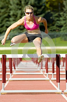 Athlete Jumping Over Hurdles on a Track