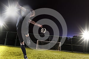 Athlete kicking soccer ball into a goal