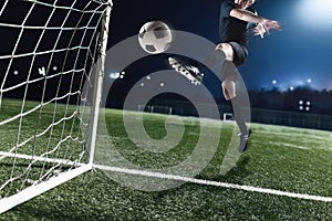 Athlete kicking soccer ball into a goal at night