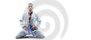 Athlete in a kimono with a blue belt sits and waits for the opponent. Concept of karate, sambo, jujitsu