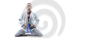 Athlete in a kimono with a blue belt sits and waits for the opponent. Concept of karate, sambo, jujitsu photo