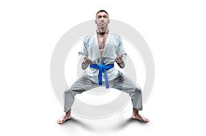 Athlete in a kimono with a blue belt stands in a fighting position. Concept of karate, sambo, jujitsu photo