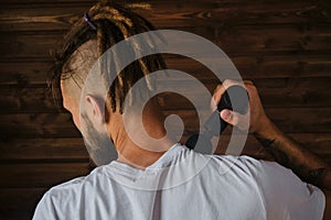 Athlete kneads neck and back muscles after training, rear view. The concept of healthy lifestyle. Caucasian man with dreadlocks