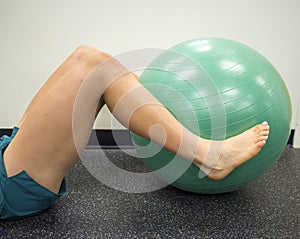 Athlete lying down with her legs around a fitness ball working out and doing exercises