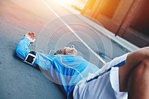 Athlete lying on the street after running session and resting at sunset