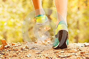 Athlete makes a morning run through the autumn forest. Foliage on a park treadmill and athlete`s feet.