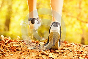 Athlete makes a morning run through the autumn forest. Foliage on a park treadmill and athlete`s feet.