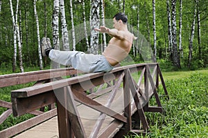 Athlete man balances on railing of wooden bridge photo