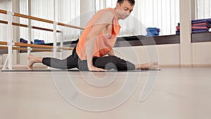 Athlete-man makes torso turns, sitting on the floor in the gym, yoga exercises.Health, life, flexibility