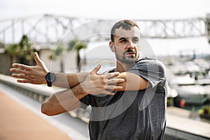 Athlete man stretching before running in the street. Active and sport young male in sportswear warming up for training