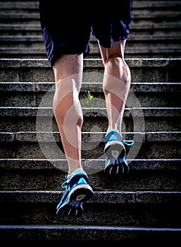 Athlete man with strong leg muscles training and running urban city staircase in sport fitness and healthy lifestyle concept