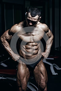 Athlete muscular bodybuilder man demonstrates his muscles in the gym