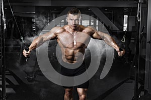 Athlete muscular bodybuilder training on simulator in the gym