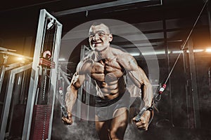 Athlete muscular bodybuilder training on simulator in the gym