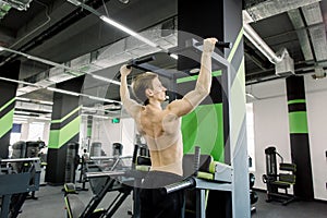 Athlete muscular fitness sportsman pulling up on horizontal bar in a gym. Athletic Caucasian man making pull-up