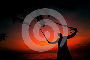 The athlete performs exercises on the beach with fitness straps