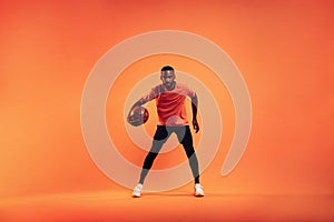 Athlete playing with basket ball. Young male practicing basketball in studio