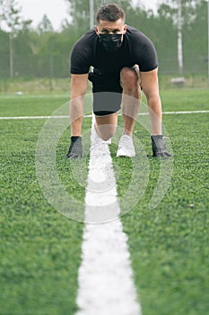 The athlete prepared to run. The athlete sports in a medical mask and gloves