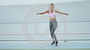 Athlete with prosthetic leg jumping sideways on track. Girl training at stadium