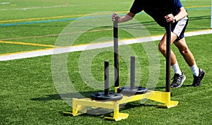Athlete pushing a sled with weights on a turf field