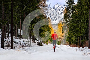 Athlete in red run under winter mountians photo