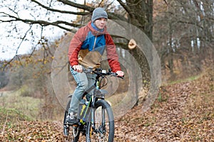 Athlete rides a bicycle in the nature at high speed in autumn