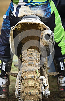 Athlete riding a sports motorbike and muddy wheel on a motocross racing event