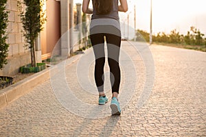 Athlete runner feet running on road closeup on shoe. Fitness sunrise jog workout wellness concept.