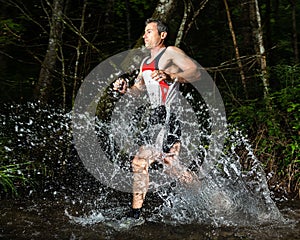 An athlete is running through a streambed