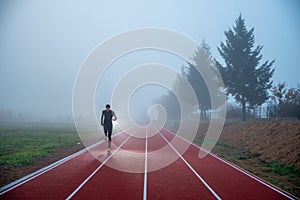 Athlete at the Running track with red lines over misty blue sky. Sport photo, edit space