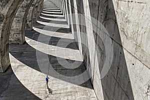 Athlete runs under concrete arcades