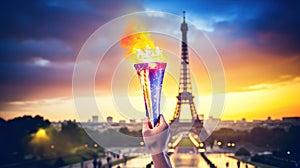 An athlete's hand holds lit torch in front of Eiffel Tower at sunset, evoking inspiration and victory. Olympics in