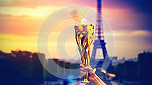 An athlete& x27;s hand holds lit torch in front of Eiffel Tower at sunset, evoking inspiration and victory. Olympics in