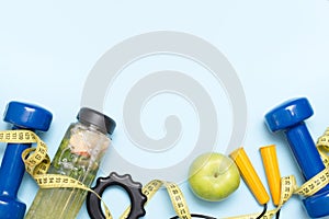 Athlete`s set with apple, dumbbells and bottle of water on blue background with copy space