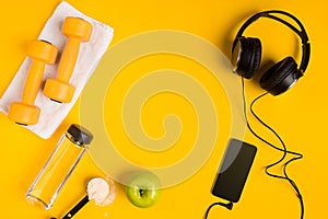 Athlete`s set with female clothing, dumbbells and bottle of water on yellow background