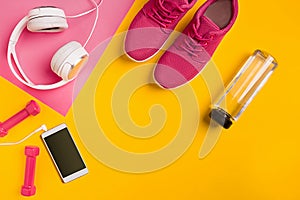 Athlete`s set with female clothing, dumbbells and bottle of water on yellow background