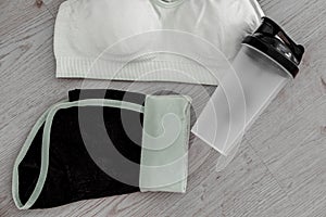Athlete`s set with female clothing, sport bra, bottle of water and a belt in white and black effect