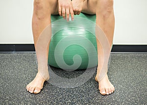 Athlete sitting on a green exercise ball taking a break between her exercises