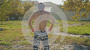 The athlete on the sports ground warms up before training. Muscular man goes in for sports in the open air. The guy in