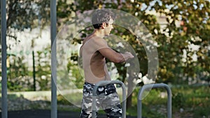 The athlete on the sports ground warms up before training. Muscular man goes in for sports in the open air. The guy in