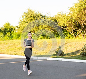 Athlete sporty woman jogging running in the city summer park.