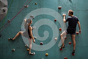 Athlete sporty woman and man practicing rock climbing on artificial rock