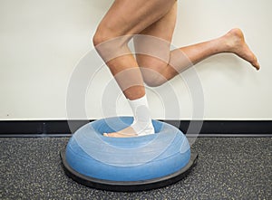 Athlete with a sprained ankle doing strengthening and balance exercises on a bosu ball