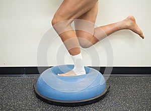 Athlete with a sprained ankle doing strengthening and balance exercises on a bosu ball photo