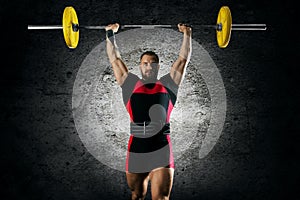 The athlete is standing with a barbell above his head.