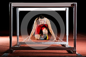 Athlete on the starting blocks with hurdles